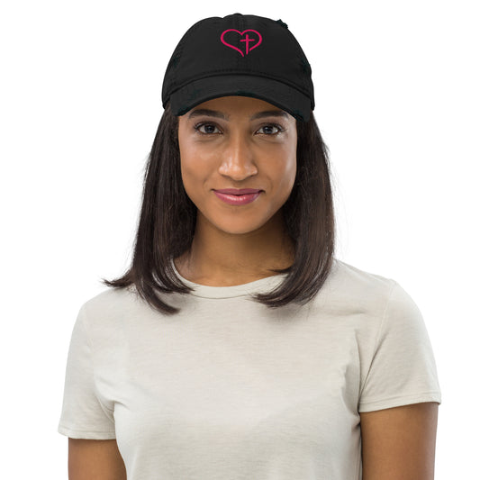 Black distressed Christian HEART OF GRACE – Distressed Cap with pink Heart and Cross embroidered on front, worn by model