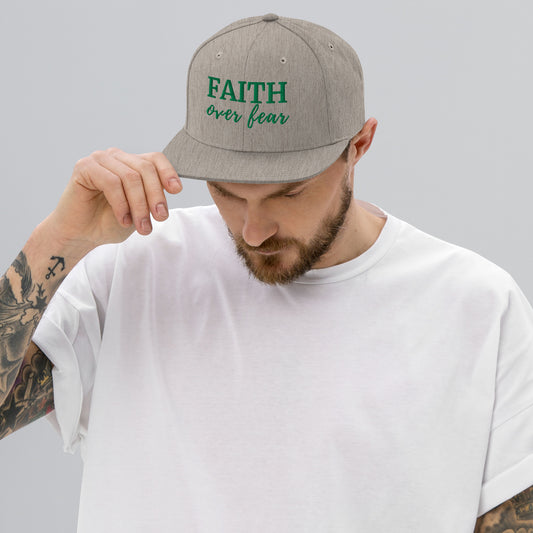Man wearing heather grey FAITH Over Fear embroidered snapback hat with green lettering