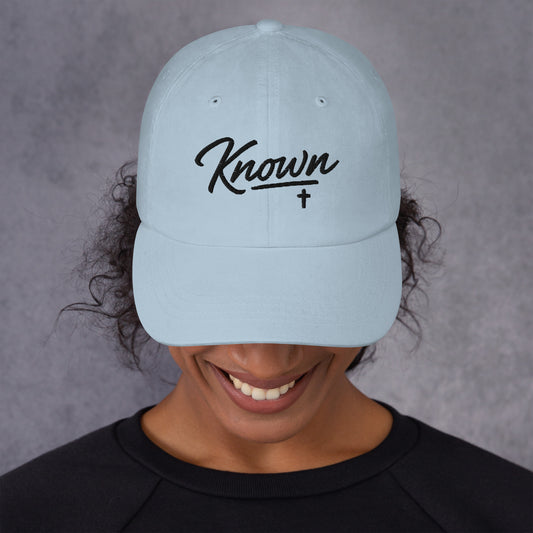 Front view of light blue Christian KNOWN Dad Hat with black script and cross embroidery