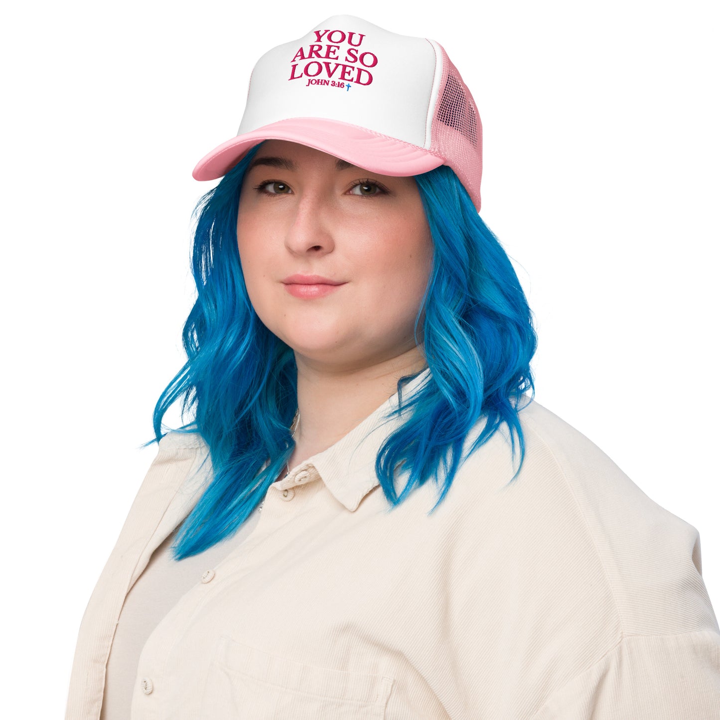 Model with blue hair wearing white and pink YOU ARE SO LOVED Christian trucker hat with bold pink lettering
